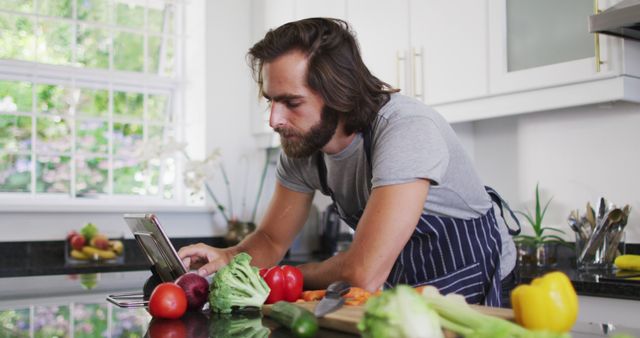 Man in apron using tablet while preparing healthy meal in modern kitchen - Download Free Stock Images Pikwizard.com