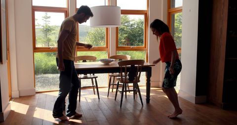 Playful Couple Enjoying Dance in Sunlit Dining Area - Download Free Stock Images Pikwizard.com