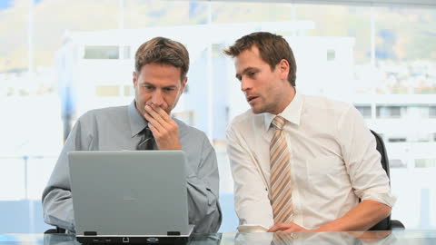 Focused Businessmen Collaborating on Laptop Project