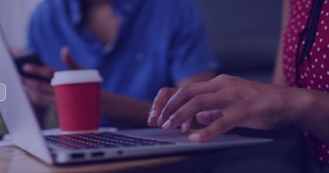 Woman Typing on Laptop While Collaborating in Cafe Setting