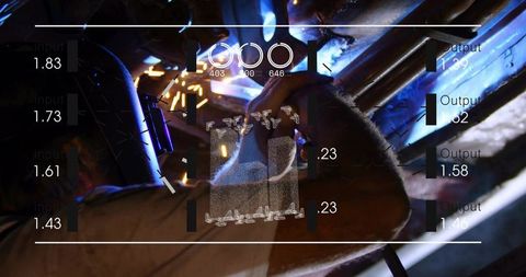 Welder grinding under vehicle frame with sparks and augmented HUD overlay for industrial precision