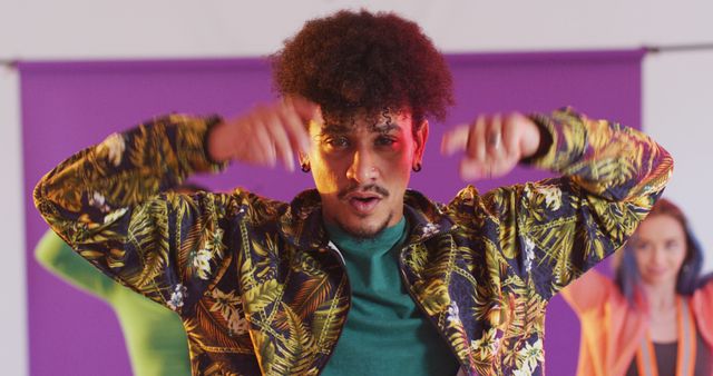 Young man dancing energetically in a studio setting wearing colorful, vibrant clothing. Ideal for use in advertisements, blogs, or websites focusing on modern dance, youth culture, fashion, and fun activities.