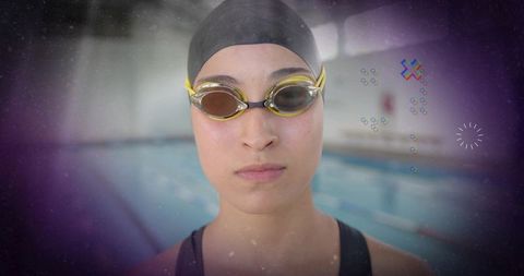 Focused athlete standing at poolside wearing swim cap and goggles