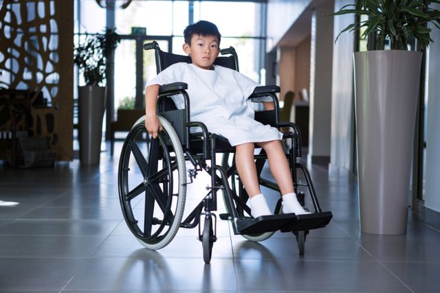 Disabled boy patient on wheelchair in hospital corridor at hospital