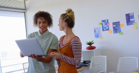 Diverse Coworkers Collaborating on Laptop in Bright Office