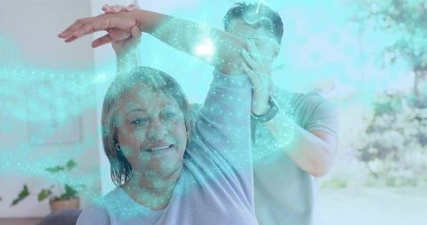 Caregiver assisting senior woman with guided arm stretch during home rehabilitation