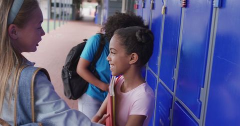 Smiling schoolgirls chatting by lockers during daytime