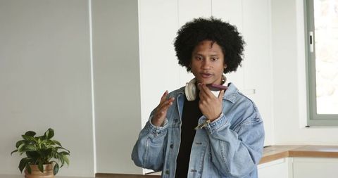 African American man speaking into smartphone while gesturing in bright kitchen