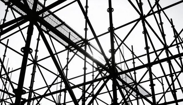 Backlit scaffolding forming dense steel lattice with grated walkway silhouette