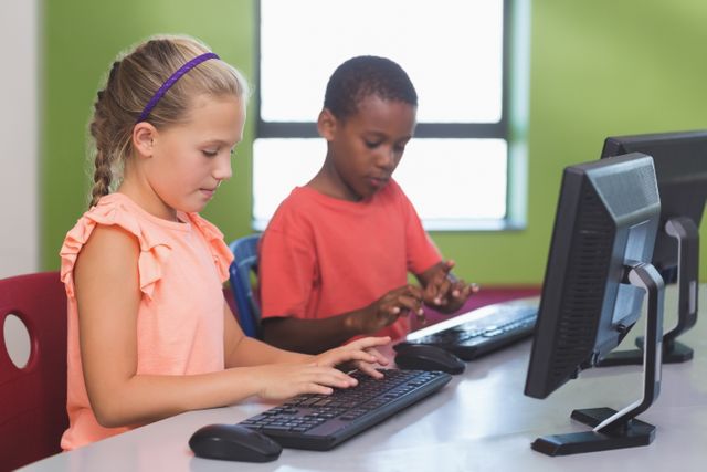 Two school children are using computers in a classroom setting, focusing on their tasks. This image can be used for educational content, technology in education, school brochures, or articles about modern learning environments.