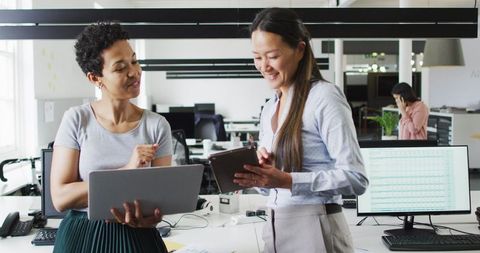 Diverse Businesswomen Collaborating with Laptop and Tablet in Modern Office