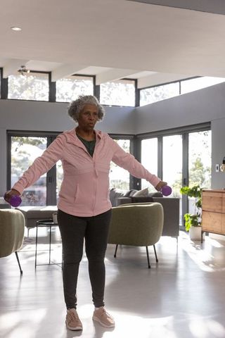 Senior african american woman lifting dumbbells at home