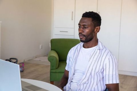 African American Professional Focused on Laptop in Minimalist Home Office