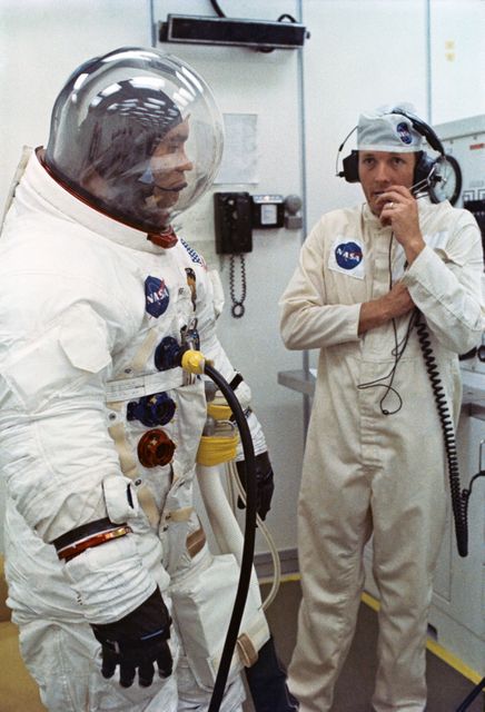 Scene showing astronaut and space suit technician preparing for Apollo 13 mission at Kennedy Space Center in 1970. Useful for educational purposes, articles on space exploration history, or exhibits showcasing Apollo missions.