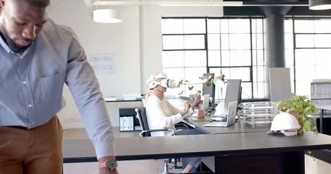 Woman Engaged in VR Work at Modern Office with Colleague Nearby