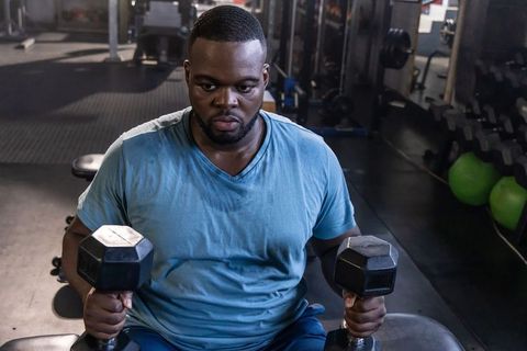 African american man lifting dumbbells on bench training strength endurance and focus