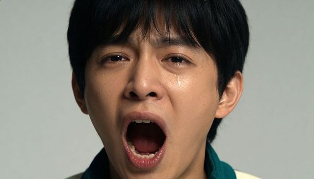 Tearful asian man crying with mouth open closeup portrait showing raw emotional pain