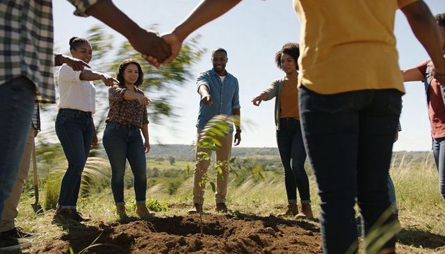 Community volunteers planting sapling in grassland circle showing unity and teamwork