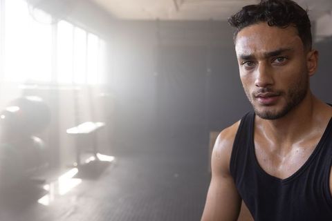 Middle eastern man sweating and training in warehouse gym, intense workout portrait of determination