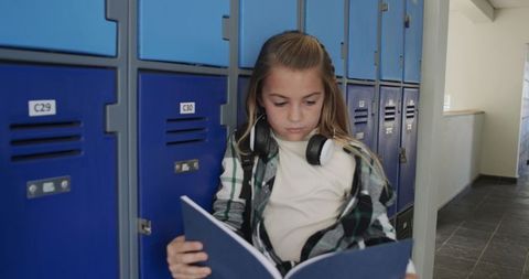 Schoolgirl Reading Notebook in Hallway with Headphones