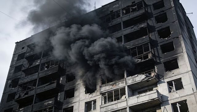 Burned highrise emitting thick black smoke from upper floors with shattered windows