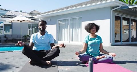 Black Couple Practicing Outdoor Yoga by Pool in Backyard Meditating in Lotus Pose for Calm