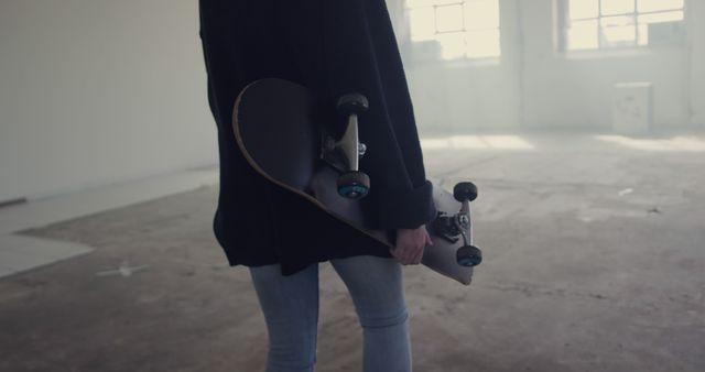 Person Holding Skateboard in Spacious Room with Light through Windows - Download Free Stock Images Pikwizard.com