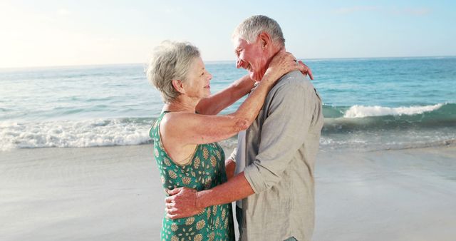 A retired couple is dancing together joyfully on a beach at sunset, symbolizing love, companionship, and the joy of spending quality time together in later years. This image can be perfect for promoting senior romance, retirement planning, leisure activities for the elderly, healthy lifestyles, holidays for seniors, or travel destinations focusing on retirees. Ideal for use in brochures, advertisements, blogs, and social media posts targeting senior citizens and their families.