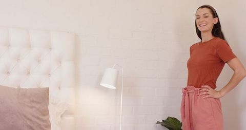 Stylish Young Woman Standing in Cozy Modern Bedroom