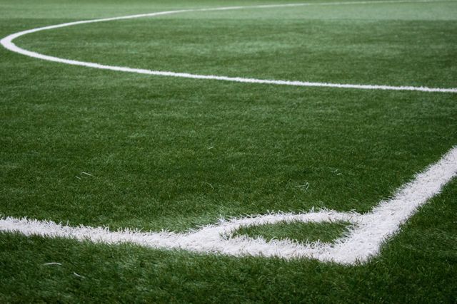 Image depicting a closeup of a corner of an artificial turf soccer field with clearly defined white lines. Suitable for use in articles about soccer fields, sports logos, stadium projects, and school sports facilities.