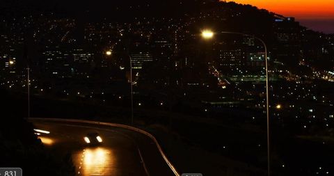 Nighttime Drive on Hillside Overlooking Vibrant Cityscape