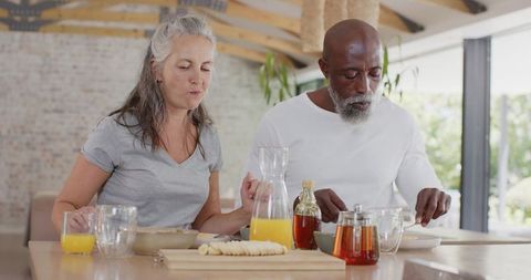Senior couple sharing sunny breakfast in modern open-plan kitchen with fresh juice and bread