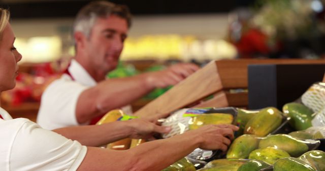 Supermarket staff placing fresh fruits and vegetables on shelves. Useful for illustrating concepts of grocery stores, fresh produce management, retail work, teamwork, daily operations in markets, and healthy eating. The scene can be used for promoting supermarket services, advertising employment in retail sectors, or highlighting freshness in food promotions.