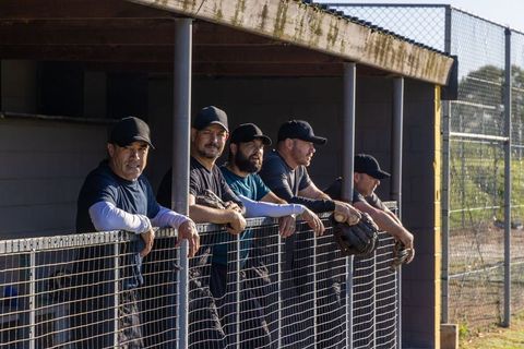 Baseball players leaning on dugout fence watching game sharing strategy and camaraderie