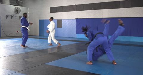 Men Practicing Judo Throws in Gymnasium
