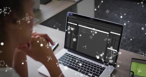 Woman analyzing terminal windows with network overlays at workplace