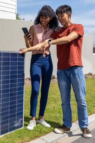 Couple checking solar panel output with smartphone, home solar, renewable energy