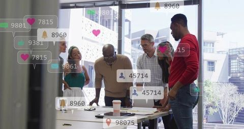 Diverse team collaborating around table with social media overlays in modern office