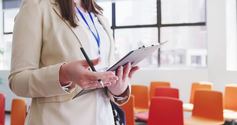 Businesswoman Holding Clipboard in Modern Office Environment - Download Free Stock Images Pikwizard.com