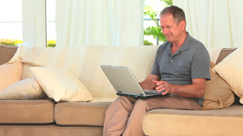 Middle Aged Man Using Laptop While Relaxing on Couch