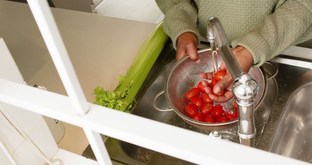 Closeup of individual washing fresh tomatoes under kitchen faucet. Might be used for topics related to food preparation, home cooking, healthy eating habits, and kitchen hygiene.