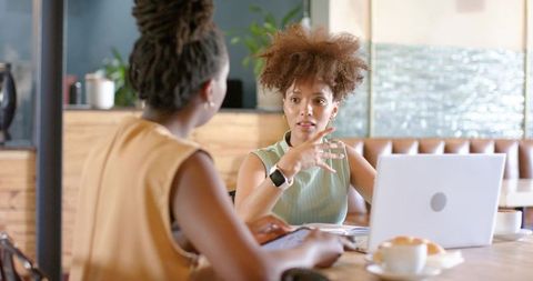 African american coworkers discussing project in cafe with laptop, tablet and coffee
