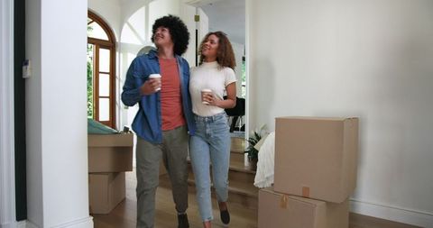 Happy couple exploring new home with moving boxes and coffee