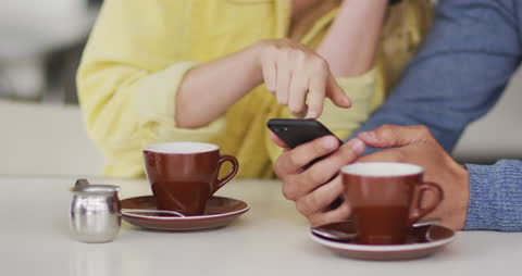 Couple Enjoying Coffee While Using Smartphone