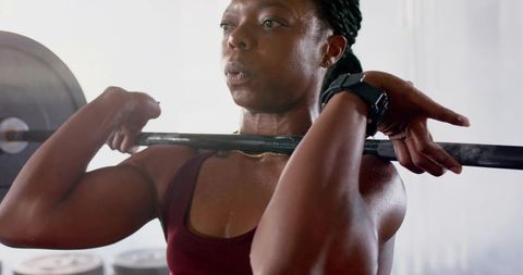 Female athlete lifting barbell in front rack demonstrating strength, focus and sweat