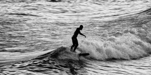 Silhouette of Surfer Riding a Wave at Sea