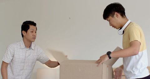 Asian Father and Son Bond through Unpacking Cardboard Box at Home