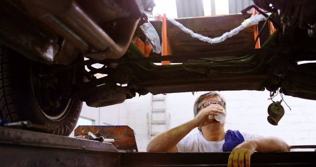 Mechanic enjoying break while working on car in garage - Download Free Stock Images Pikwizard.com