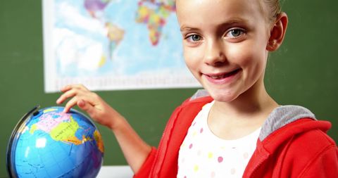 Happy Schoolgirl Exploring Globe in Classroom Setting