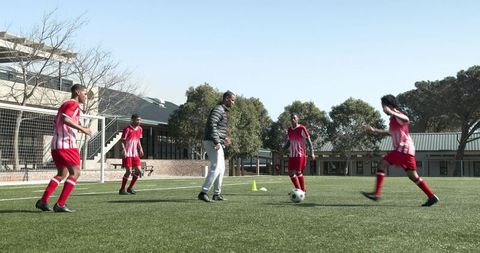 Youth soccer team practicing skills with coach in open field